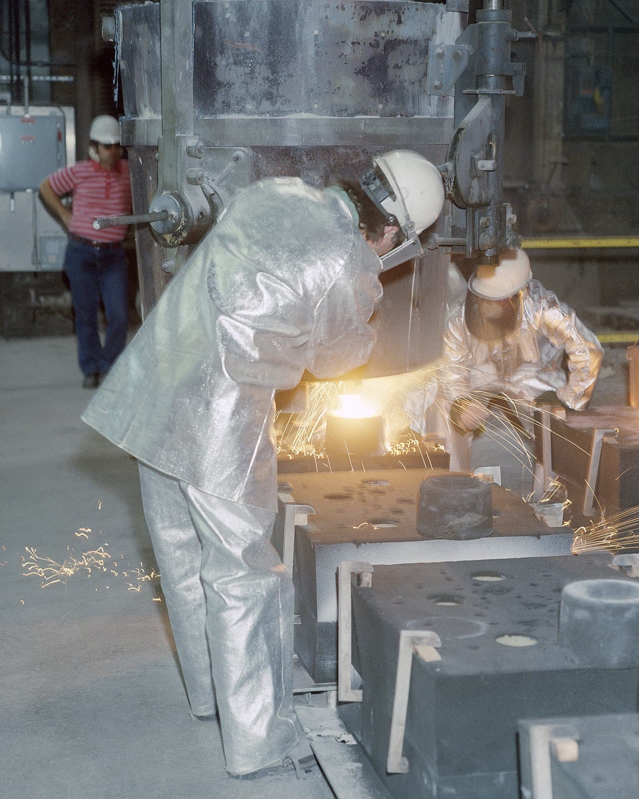 Workers pouring molten metal into a mold at a U.S. Army arsenal foundry.